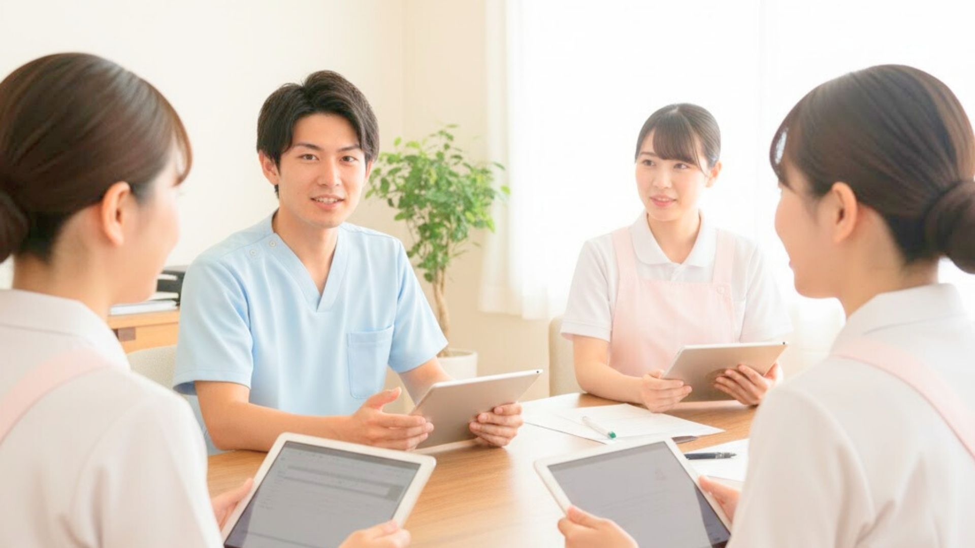 ジェスチャーで説明する男性と聞き入る女性スタッフの少人数カンファレンス